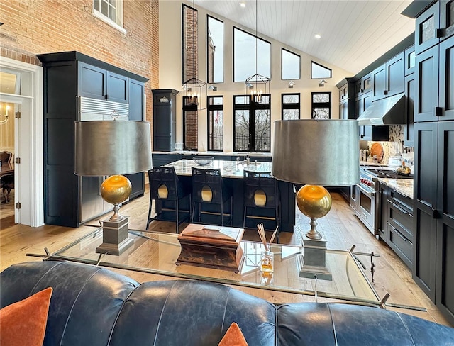 living room with brick wall, light wood-type flooring, and high vaulted ceiling