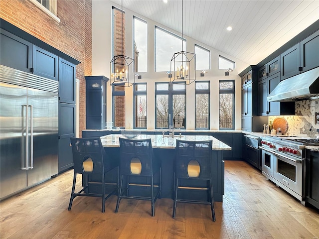 kitchen featuring an island with sink, high end appliances, a breakfast bar area, and light hardwood / wood-style flooring