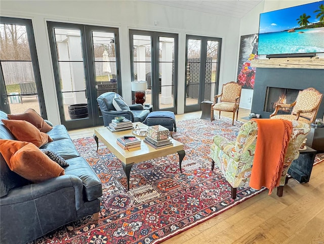 living room with french doors, a premium fireplace, hardwood / wood-style flooring, and lofted ceiling