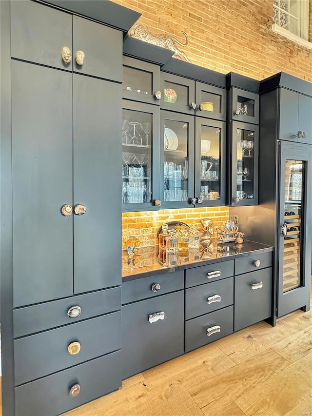 bar with beverage cooler, backsplash, and light hardwood / wood-style flooring