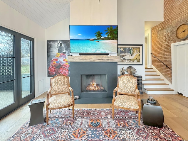 interior space with hardwood / wood-style floors, high vaulted ceiling, and brick wall