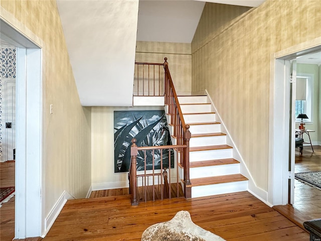 stairway with wood-type flooring and vaulted ceiling