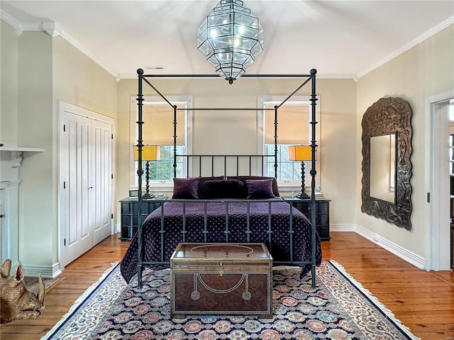 bedroom with a closet, hardwood / wood-style flooring, and crown molding