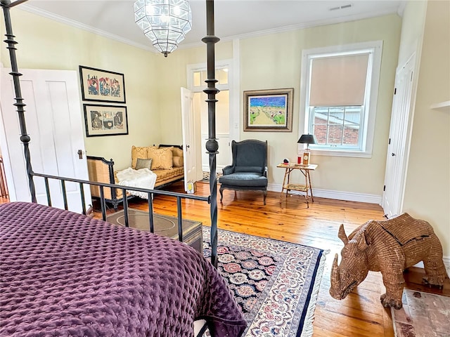 bedroom with ornamental molding, hardwood / wood-style floors, and an inviting chandelier