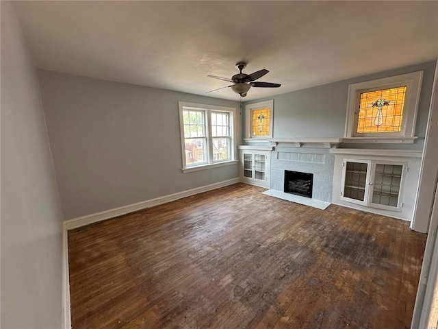 unfurnished living room with ceiling fan, dark hardwood / wood-style floors, and a brick fireplace