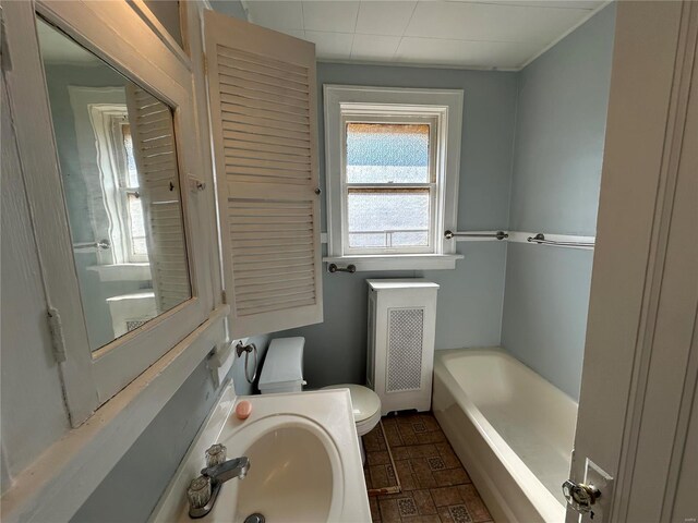 bathroom featuring a bathtub, toilet, radiator, and sink