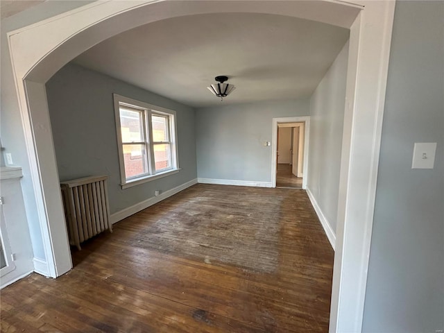 spare room featuring dark hardwood / wood-style flooring and radiator heating unit