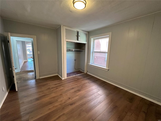 unfurnished bedroom featuring dark wood-type flooring, a textured ceiling, and a closet