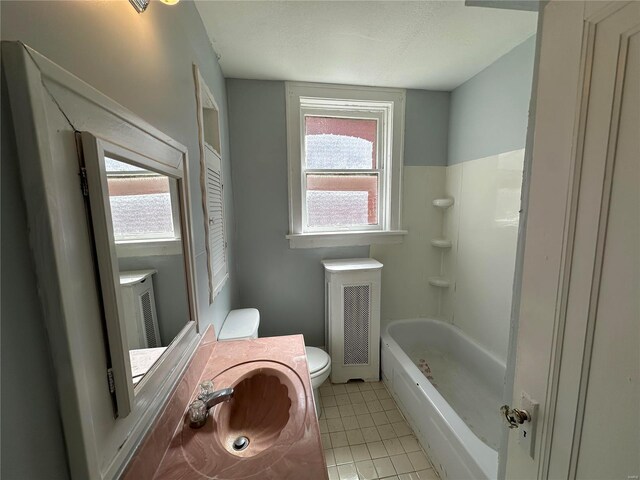 bathroom featuring a tub, toilet, plenty of natural light, and vanity