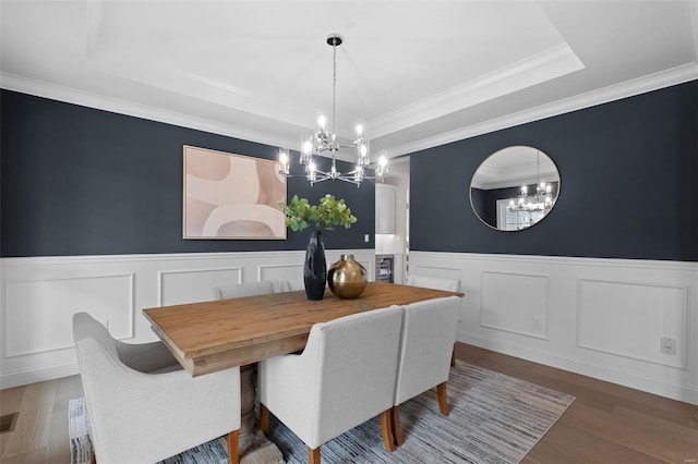 dining area with a tray ceiling, hardwood / wood-style flooring, a chandelier, and crown molding