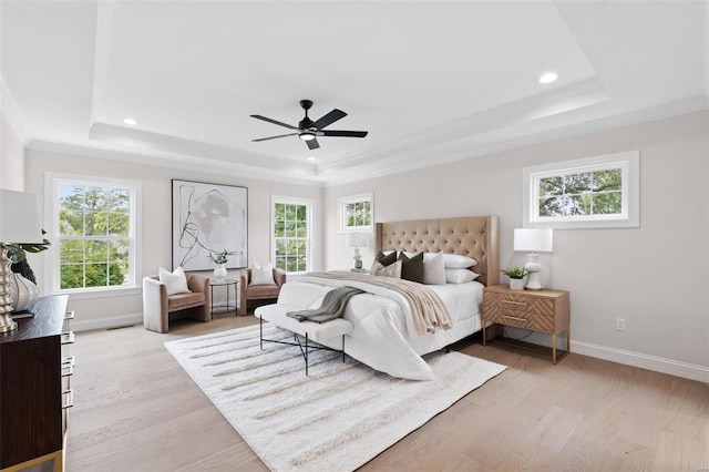 bedroom featuring a raised ceiling, ceiling fan, multiple windows, and light hardwood / wood-style floors