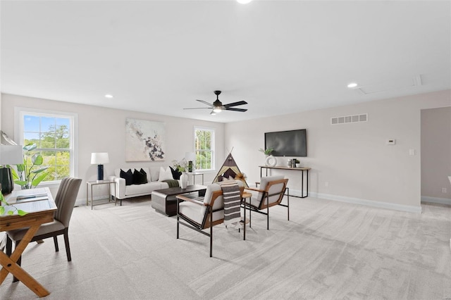 living room featuring light carpet, plenty of natural light, and ceiling fan