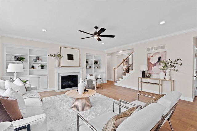 living room featuring ceiling fan, a fireplace, and light hardwood / wood-style floors