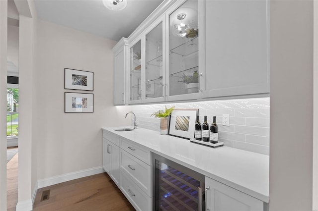 bar with white cabinetry, beverage cooler, and decorative backsplash