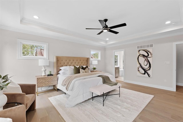 bedroom with light hardwood / wood-style flooring, ceiling fan, a raised ceiling, and multiple windows