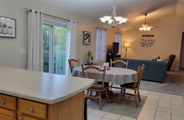 tiled dining space with ceiling fan with notable chandelier and lofted ceiling