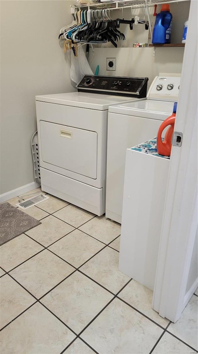 clothes washing area featuring light tile patterned floors and independent washer and dryer