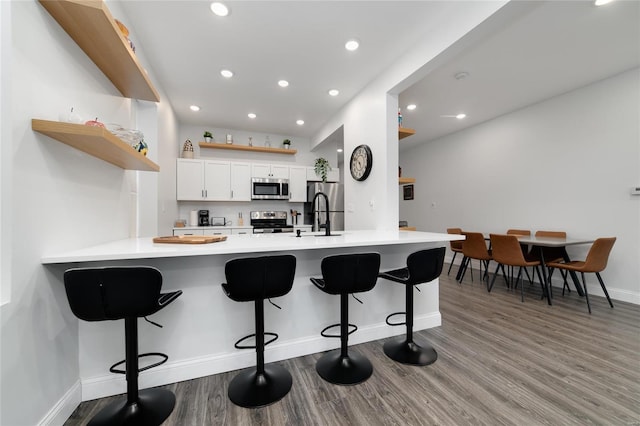 kitchen with a breakfast bar area, kitchen peninsula, white cabinetry, and stainless steel appliances