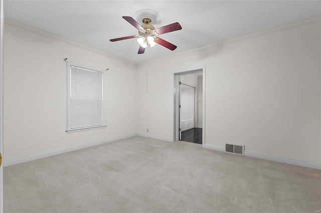 spare room featuring visible vents, carpet, ornamental molding, and a ceiling fan