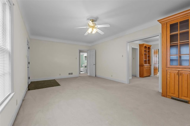 empty room featuring ceiling fan, baseboards, light colored carpet, and visible vents