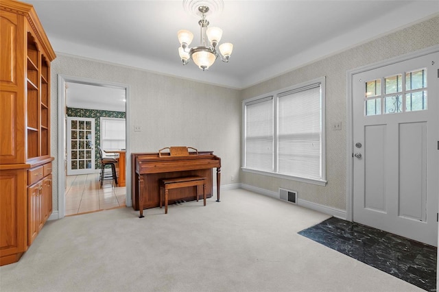 entrance foyer featuring wallpapered walls, light carpet, a notable chandelier, and visible vents