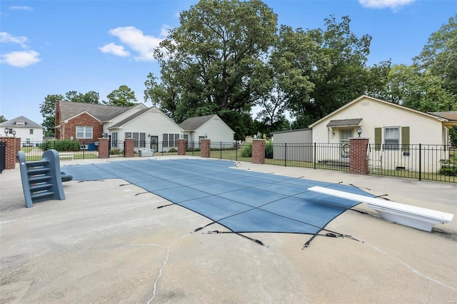 view of swimming pool featuring a diving board and a patio area