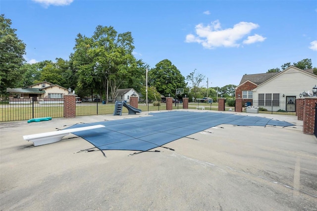 view of swimming pool with a fenced in pool, a diving board, a water slide, fence, and a patio