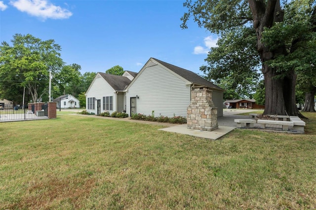 view of side of home featuring a lawn, stone siding, and fence