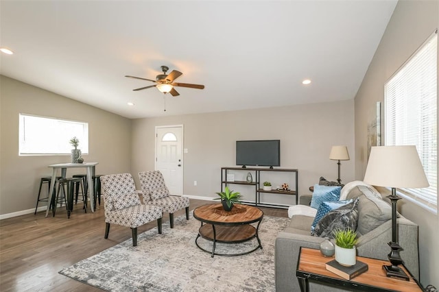 living room with ceiling fan, wood-type flooring, and vaulted ceiling