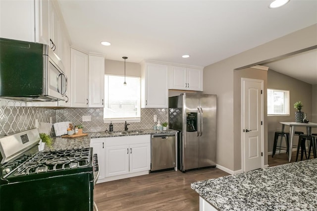 kitchen featuring decorative light fixtures, light stone countertops, appliances with stainless steel finishes, dark wood-type flooring, and white cabinetry