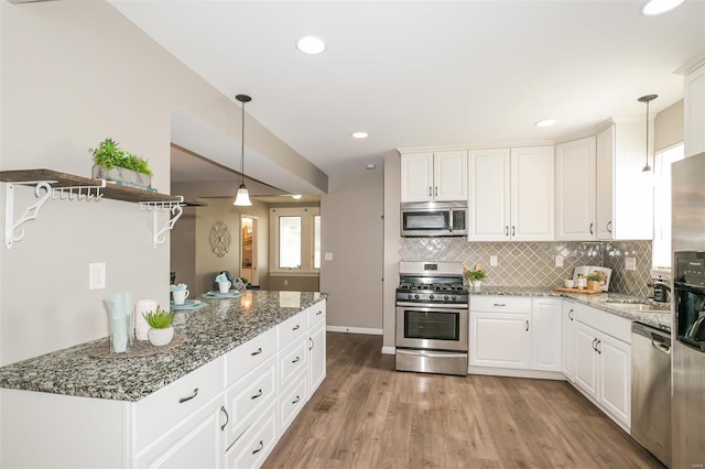 kitchen with light wood-type flooring, appliances with stainless steel finishes, white cabinetry, and pendant lighting