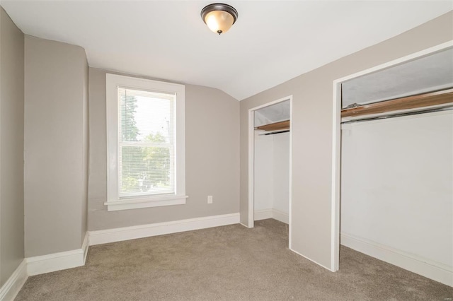 unfurnished bedroom featuring vaulted ceiling and light colored carpet