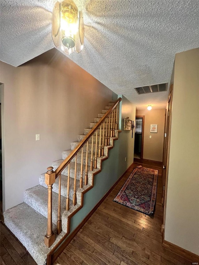 staircase featuring a textured ceiling and hardwood / wood-style floors