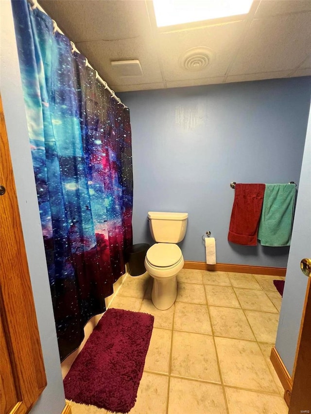 bathroom with a paneled ceiling, toilet, and tile patterned floors