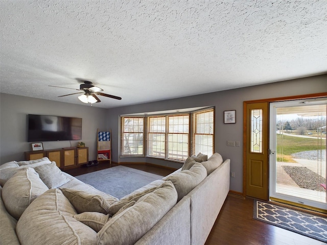 living room with a textured ceiling, ceiling fan, and dark hardwood / wood-style flooring