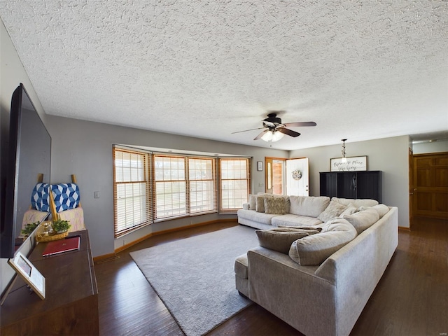 living room featuring dark wood-type flooring, ceiling fan, and a textured ceiling