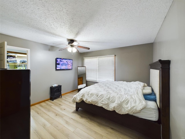 bedroom featuring light wood-type flooring, a textured ceiling, and ceiling fan