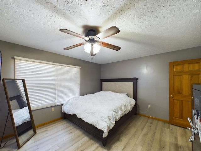 bedroom with a textured ceiling, ceiling fan, and light wood-type flooring