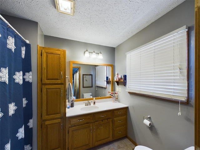 bathroom featuring vanity, a textured ceiling, toilet, and tile patterned floors