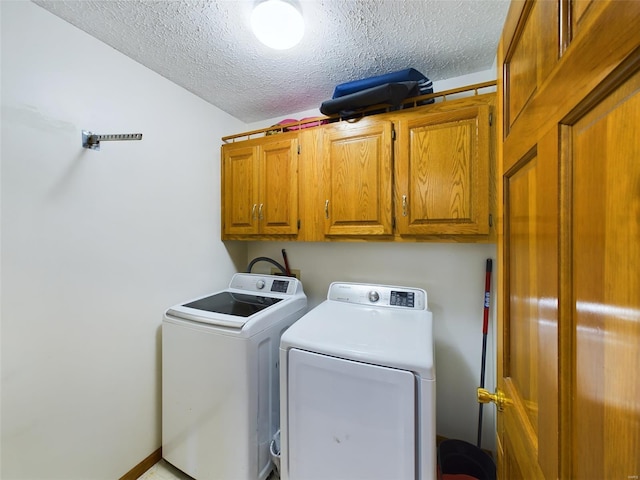 laundry area featuring a textured ceiling, cabinets, and washing machine and clothes dryer