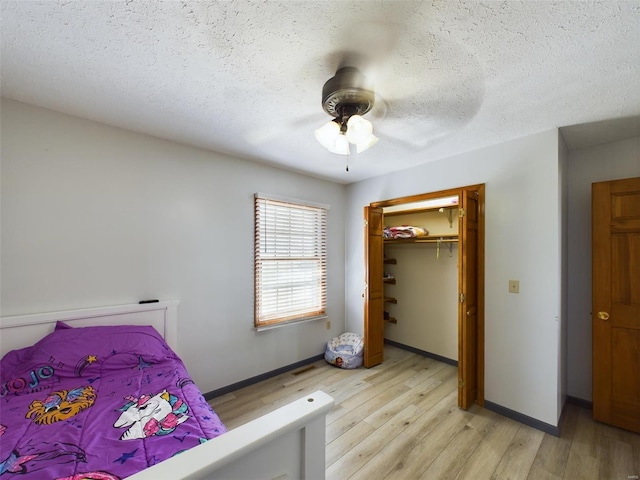 bedroom with a textured ceiling, light hardwood / wood-style flooring, ceiling fan, and a closet