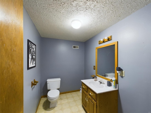 bathroom with vanity, toilet, and a textured ceiling