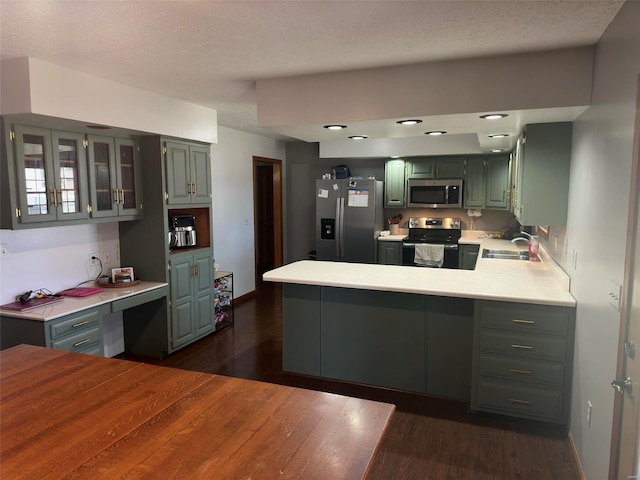 kitchen featuring dark wood-type flooring, stainless steel appliances, kitchen peninsula, and sink