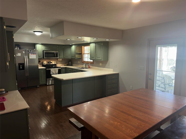 kitchen featuring appliances with stainless steel finishes, a healthy amount of sunlight, kitchen peninsula, and dark wood-type flooring