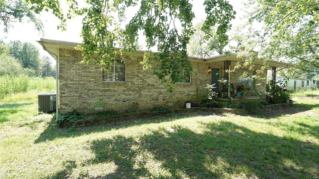 exterior space with central AC and a lawn