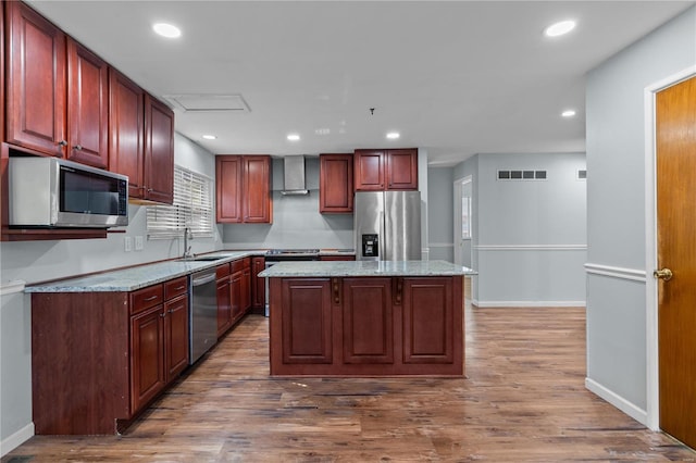 kitchen featuring light stone countertops, wall chimney range hood, a kitchen island, dark hardwood / wood-style flooring, and stainless steel appliances