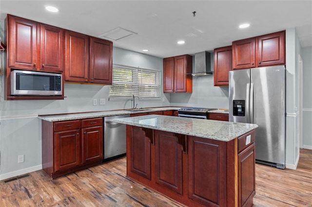 kitchen with wall chimney range hood, light hardwood / wood-style flooring, and stainless steel appliances