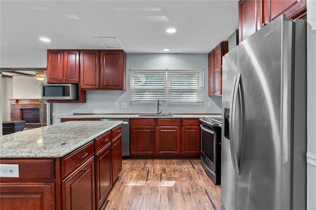 kitchen featuring a kitchen island, light stone countertops, sink, light hardwood / wood-style floors, and stainless steel appliances