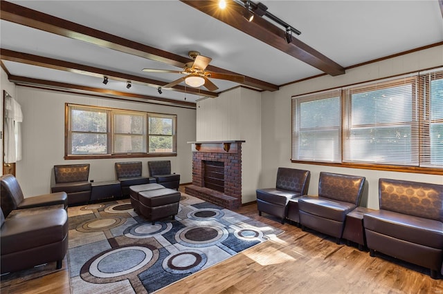 living room featuring hardwood / wood-style flooring, beamed ceiling, a fireplace, and ceiling fan