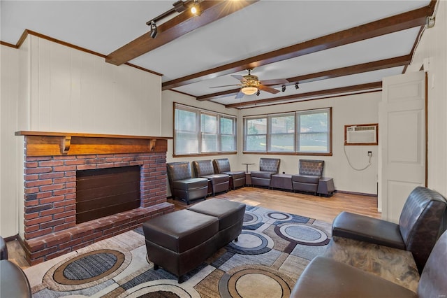 living room featuring beamed ceiling, a wall unit AC, light hardwood / wood-style floors, and plenty of natural light